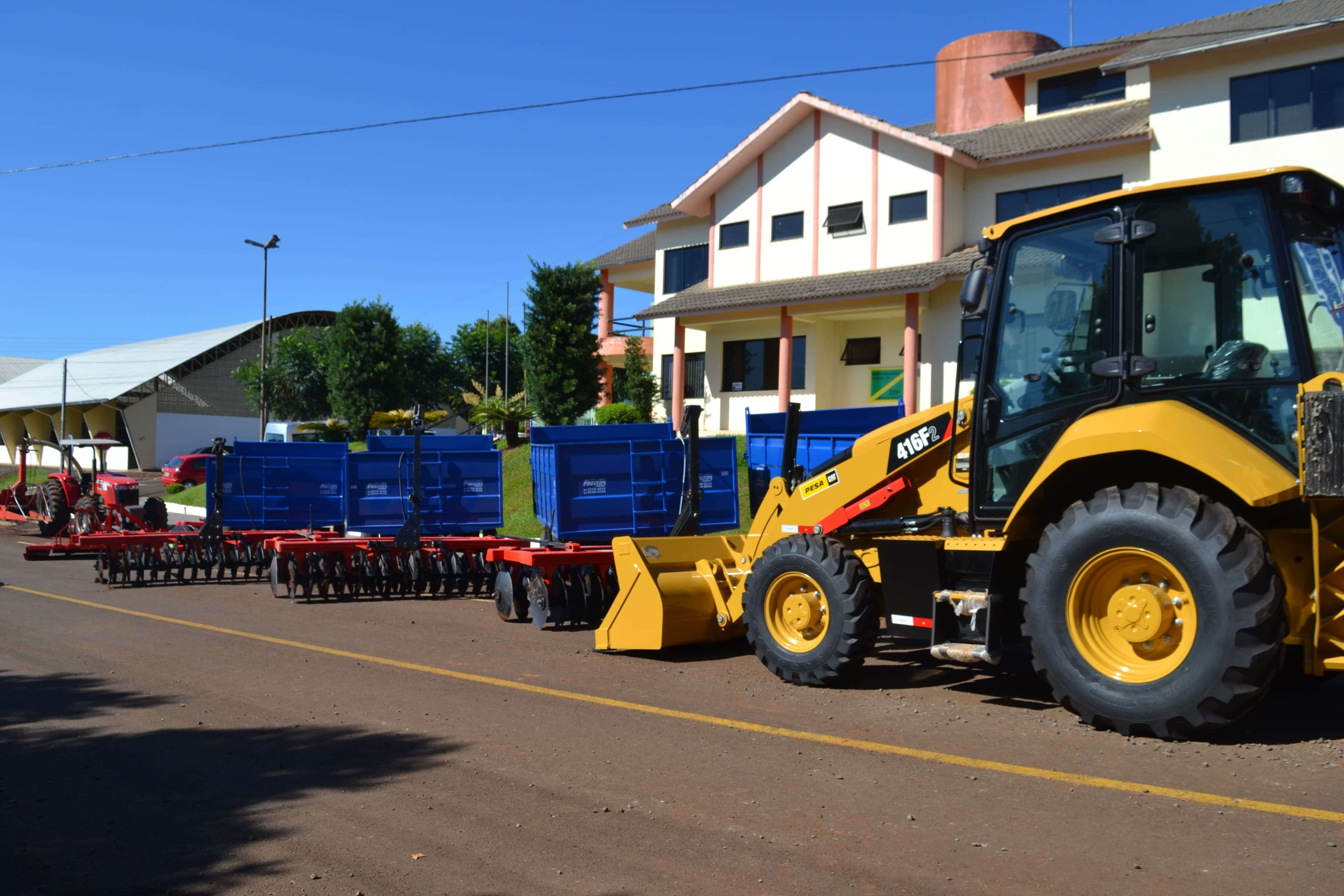 Seguro para Máquinas e Equipamentos: Um trator estacionado, perto de seus equipamentos, em frente a uma empresa.